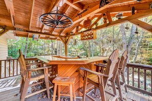 Eine Holzhütte mit einer Terrasse, einem Spinnrad und Blick auf den Wald.