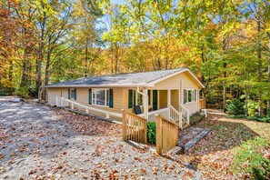 Ein eingeschossiges Blockhaus mit Veranda, umgeben von Bäumen im Herbstlaub.
