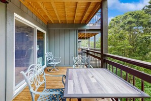 Terraza de madera con mesa y sillas, con vistas a un área boscosa.