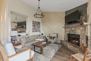 A cozy living room with a stone fireplace, a large flat-screen TV, and a comfortable seating area. - Marla on the Mountain - Stunning Views, Sugar Mountain (Sugar Mountain)
