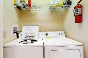 A laundry area with a white washing machine, a dryer, and a fire extinguisher mounted on the wall. - The Owl's Nest at The Reserve- Condo on Sugar Mountain with Amazing Views, Gas Fireplace! (Banner Elk)