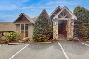 A building with a stone entrance, a wooden door, and a small porch area. - The Owl's Nest at The Reserve- Condo on Sugar Mountain with Amazing Views, Gas Fireplace! (Banner Elk)