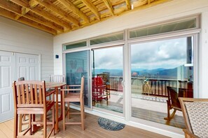 A covered patio with a wooden ceiling, a dining table with chairs, and a sliding glass door leading to a deck with a view of the mountains. - The Owl's Nest at The Reserve- Condo on Sugar Mountain with Amazing Views, Gas Fireplace! (Banner Elk)