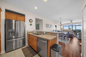 A modern kitchen with stainless steel appliances, wooden cabinets, and a view to the living area. - The Owl's Nest at The Reserve- Condo on Sugar Mountain with Amazing Views, Gas Fireplace! (Banner Elk)