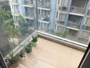 Ein Balkon mit Blumentöpfen und Blick auf ein mehrstöckiges Gebäude mit Balkonen und Klimaanlagen.