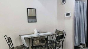 A small dining area with a table and four chairs, a clock, and a curtain on the wall. - XYZ’s Condo-One Palm Tree Villas, Newport: 6-Min Walk to NAIA T3 via Runway MNL (Unknown)