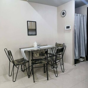 A small dining area with a table and four chairs, a clock, and a curtain on the wall. - XYZ’s Condo-One Palm Tree Villas, Newport: 6-Min Walk to NAIA T3 via Runway MNL (Unknown)