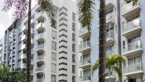 A modern residential building with multiple balconies and a swimming pool area with palm trees and planters. - XYZ’s Condo-One Palm Tree Villas, Newport: 6-Min Walk to NAIA T3 via Runway MNL (Unknown)