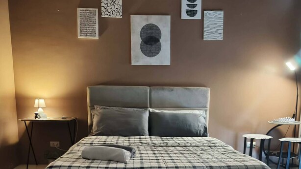 A bedroom with a bed, pillows, a nightstand, a lamp, and wall art. - XYZ’s Condo-One Palm Tree Villas, Newport: 6-Min Walk to NAIA T3 via Runway MNL (Unknown)