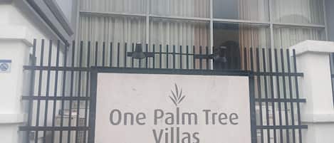 En lukket indgang til One Palm Tree Villas med et skilt.
