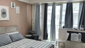 A bedroom with a bed, a desk, a chair, and a window with curtains. - XYZ’s Condo-One Palm Tree Villas, Newport: 6-Min Walk to NAIA T3 via Runway MNL (Unknown)