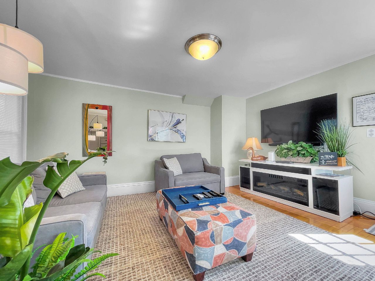A living room with a sofa, a coffee table, a TV, and a plant.