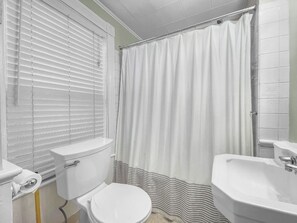 Un baño con inodoro, lavabo y cortina de ducha.