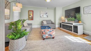 Een woonkamer met een bank, een poef en een tv-meubel.
