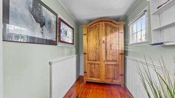 Un couloir avec une porte en bois, des rampes blanches et des œuvres d’art accrochées aux murs.