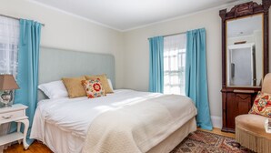 Un dormitorio con cama, mesita de noche, lámpara, silla y un espejo grande.