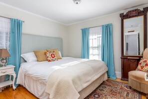 Une chambre à coucher comprenant un lit, une table de chevet, une lampe, une chaise et un grand miroir.
