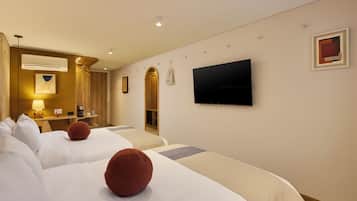 A hotel room with two beds, a TV, a mirror, and a coffee machine.