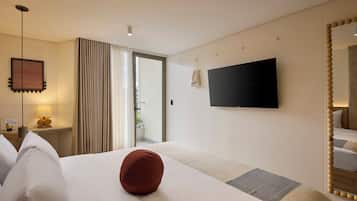 A hotel room with a bed, a television, a mirror, and a window with curtains.