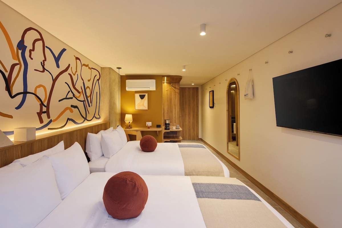 Habitación de hotel con dos camas, un cuadro abstracto grande, un televisor de pantalla plana y una cafetera.
