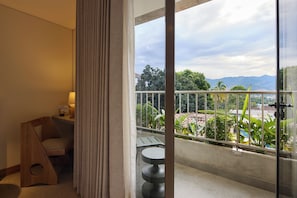 Un balcón con vistas a un jardín ajardinado y montañas distantes.