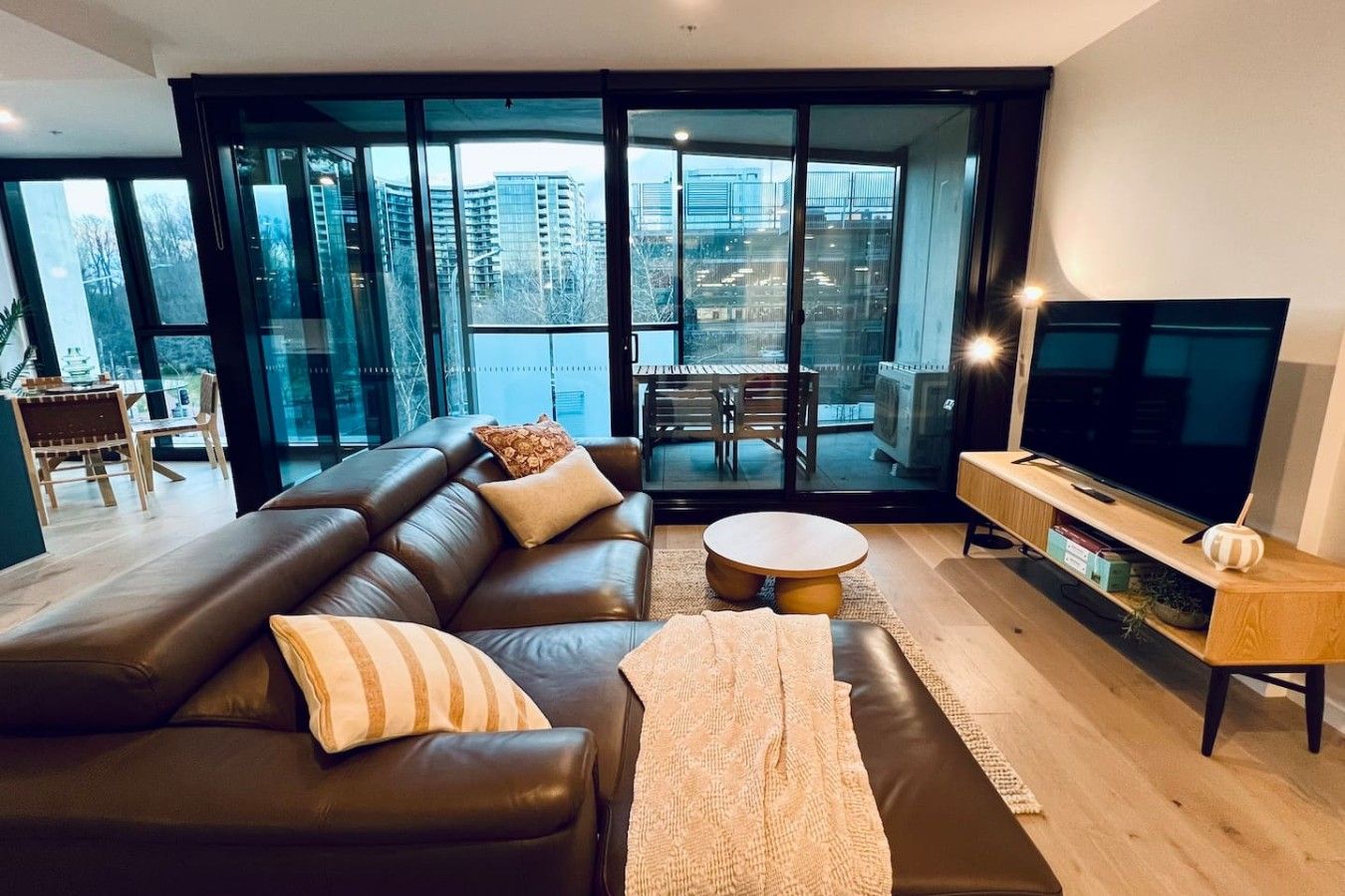Ein modernes Wohnzimmer mit einer Ledersofa, einem runden Couchtisch und einem Flachbildfernseher.