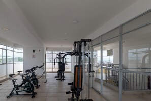 A gym with exercise equipment, large windows, and a view of the city. - Cartagena Getaway | 3-Bedroom Near the Beach + Rooftop Pool (Cartagena de Indias)