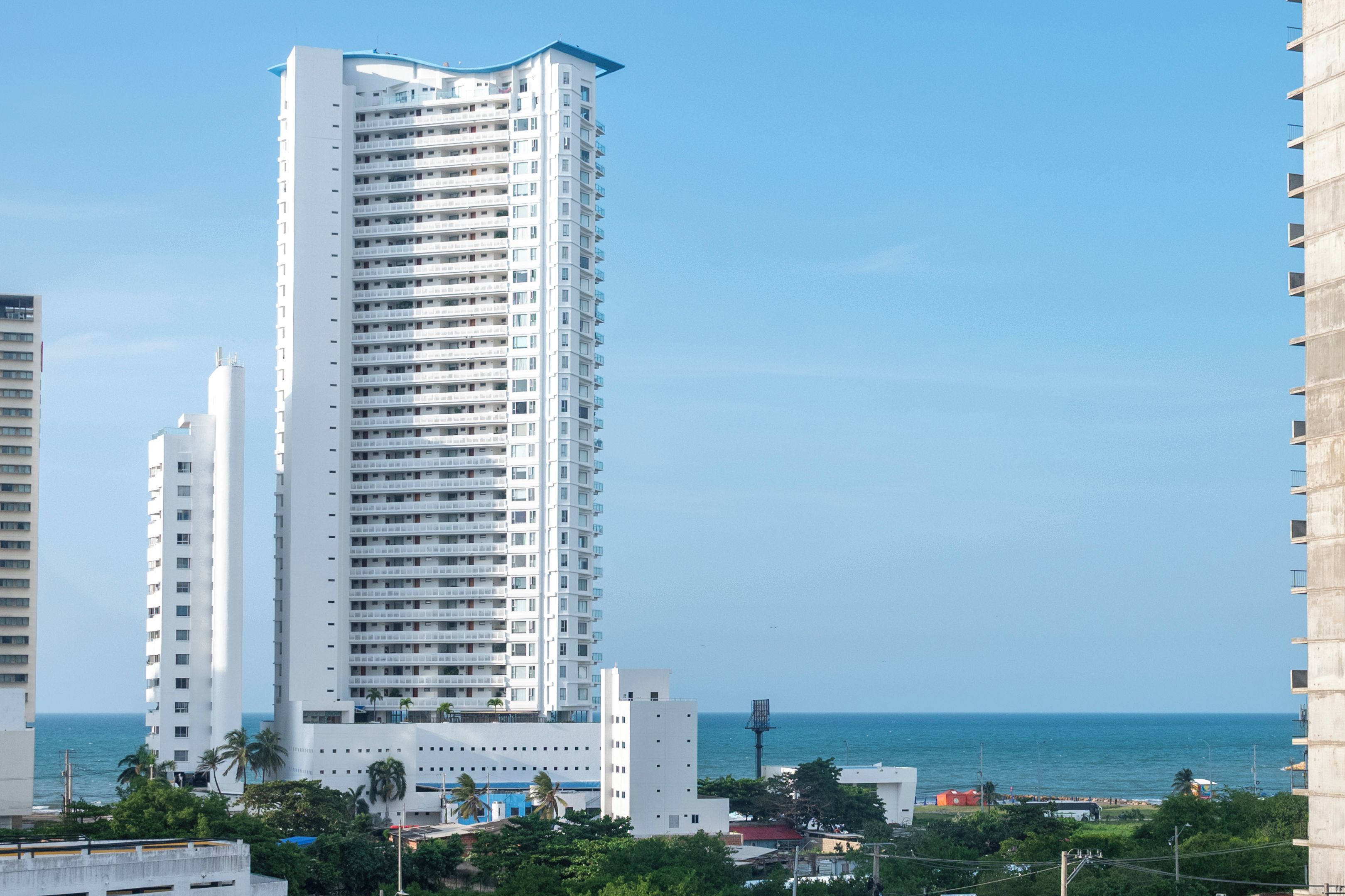 Ein Hochhaus mit mehreren Balkonen, freiem Blick auf den Ozean und einer Küstenlandschaft.