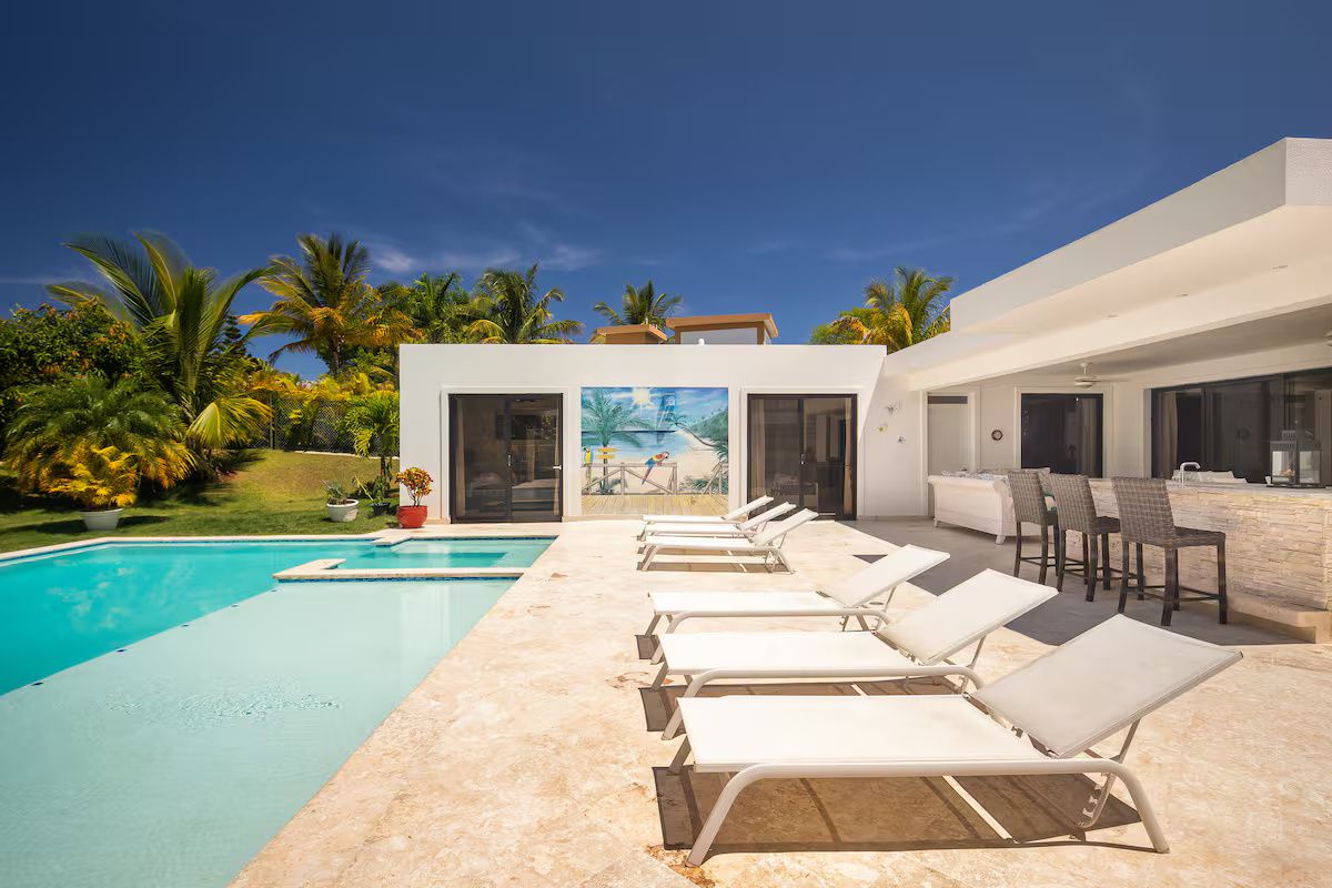 Ein moderner Poolbereich mit Liegestühlen und einer Bar.