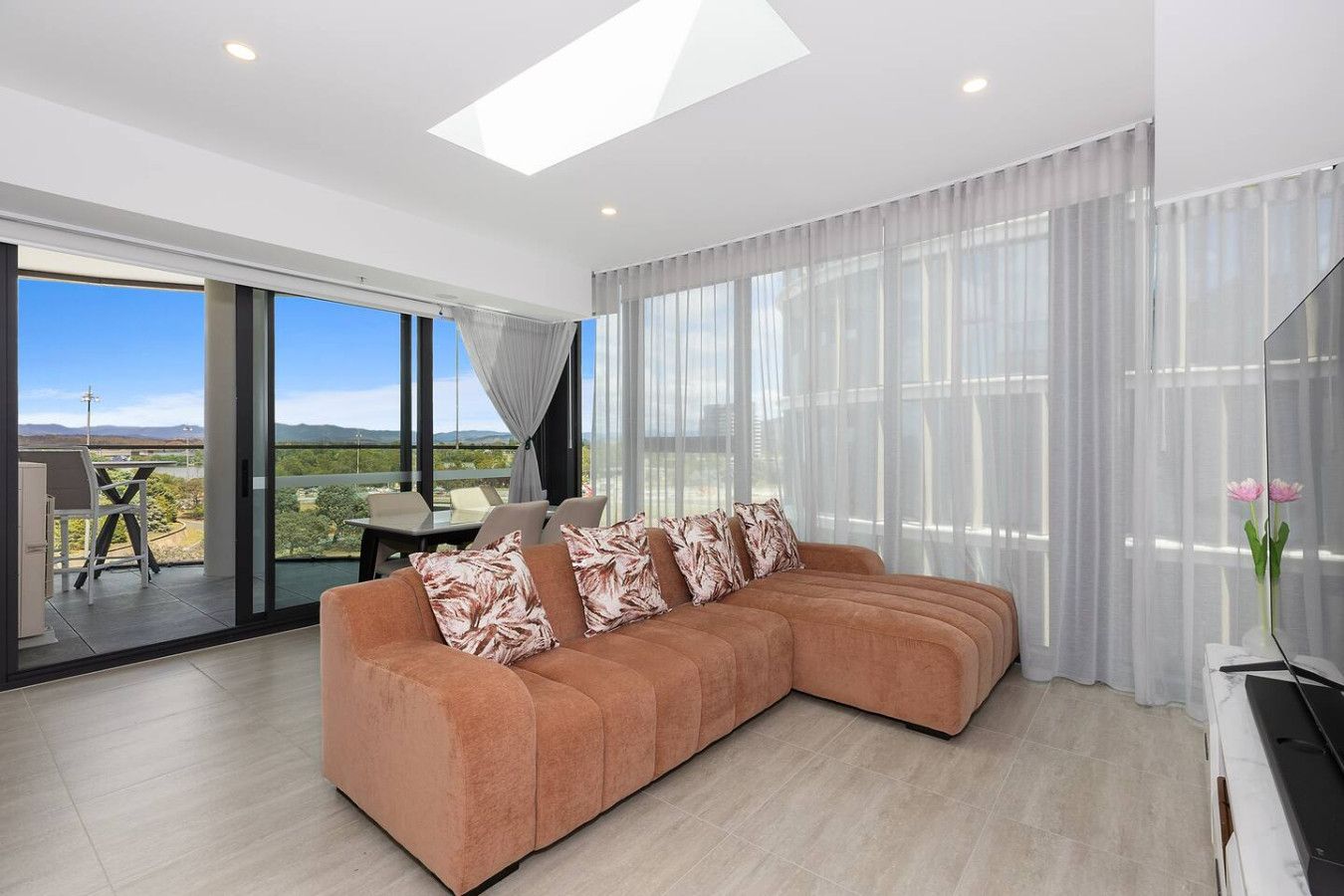 A modern living room with a sectional sofa, large windows, and a view of the outdoors.