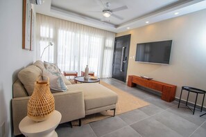 Ein modernes Wohnzimmer mit einer Couch, einem Couchtisch und einem an der Wand befestigten Fernseher.