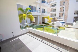 Eine moderne Wohnung mit Balkon, Glasgeländer und Blick auf einen Innenhof mit Palmen.