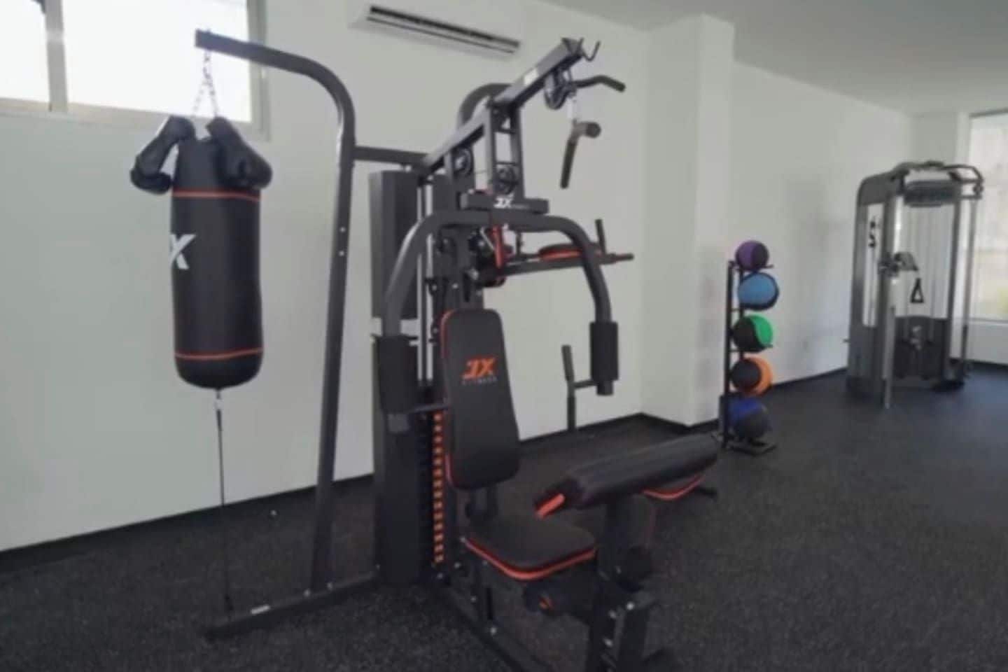 Une salle de sport équipée de matériel d’exercice, d’un sac de frappe et d’un banc.