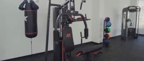 Une salle de sport équipée de matériel d’exercice, d’un sac de frappe et d’un banc.