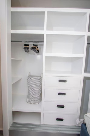 A white closet with multiple shelves and drawers, a striped hanging bag, and a pair of striped socks. - Stylish New 2-Bedroom Apartment with Pools & Gym (Cabarete)