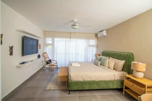 Ein Schlafzimmer mit Bett, Sessel, Fernseher und Deckenventilator.