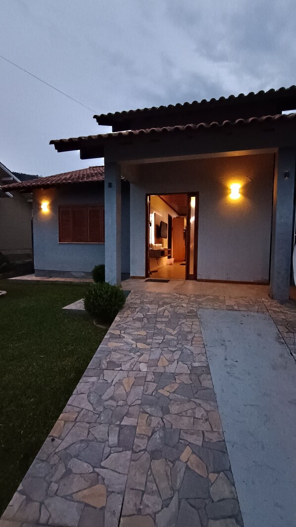 A house with a stone pathway leading to the entrance, a tiled roof, and two wall-mounted lights.