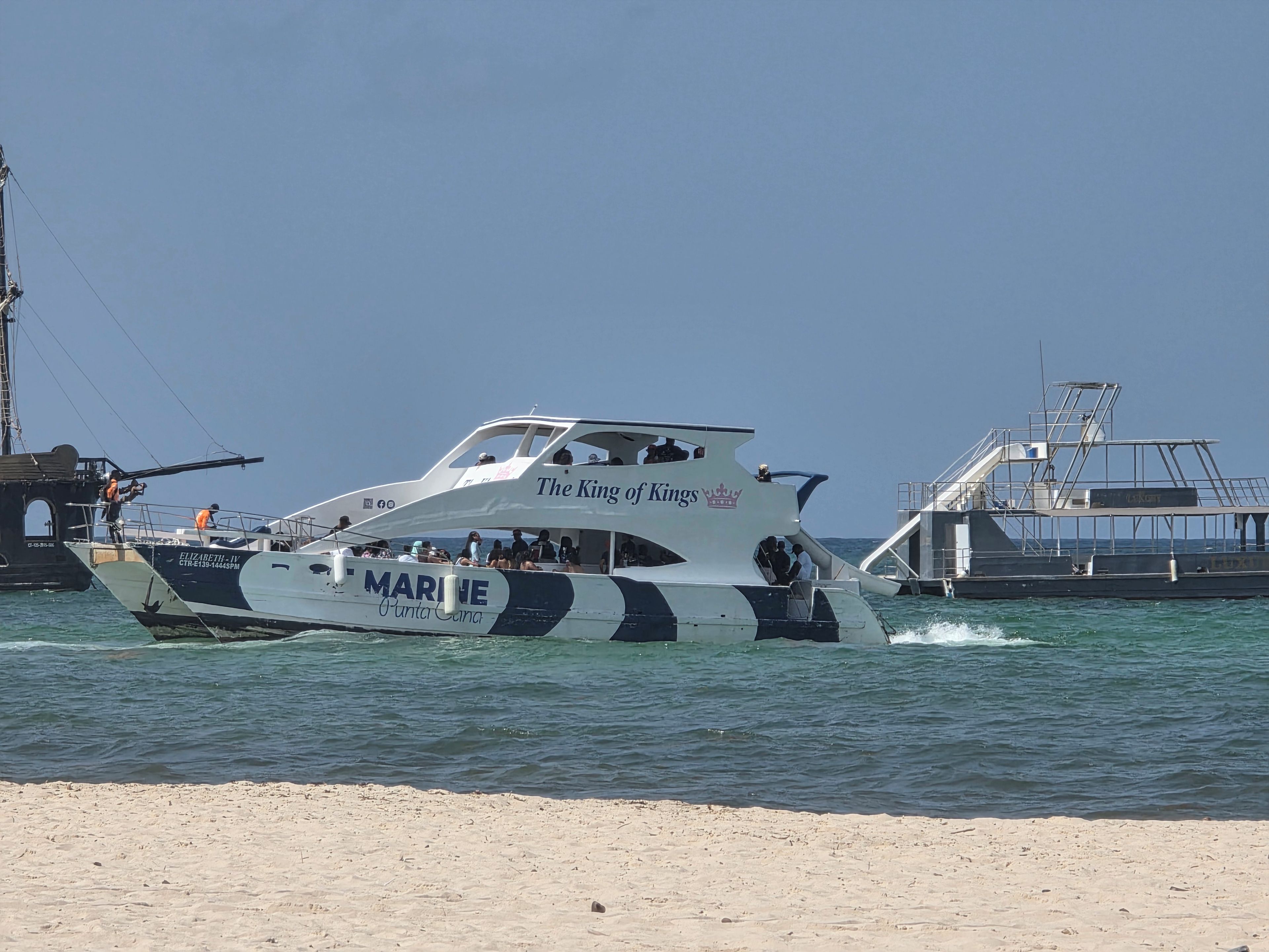 Una barca chiamata 'The King of Kings' con la scritta 'MARINE Punta Cana' sul fianco, ormeggiata su una spiaggia sabbiosa.