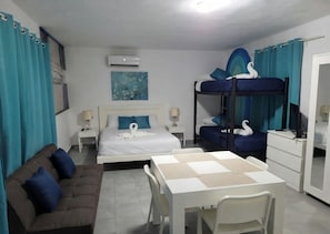 Een hotelkamer met een stapelbed, een slaapbank, een eettafel en een bureau.