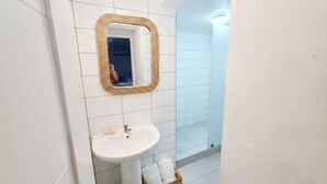 A bathroom with a white sink, a mirror with a woven frame, and a glass shower enclosure. - Gran sol caribe corales punta cana (Punta Cana)