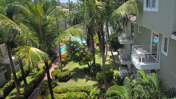 A residential building with a pool, surrounded by palm trees and well-maintained gardens. - Gran sol caribe corales punta cana (Punta Cana)