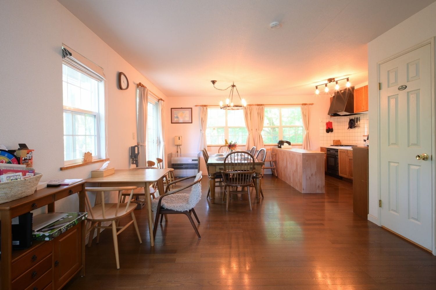 A spacious kitchen with wooden flooring, a dining area with a table and chairs, and a kitchen counter.