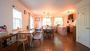 A spacious kitchen with wooden flooring, a dining area with a table and chairs, and a kitchen counter.
