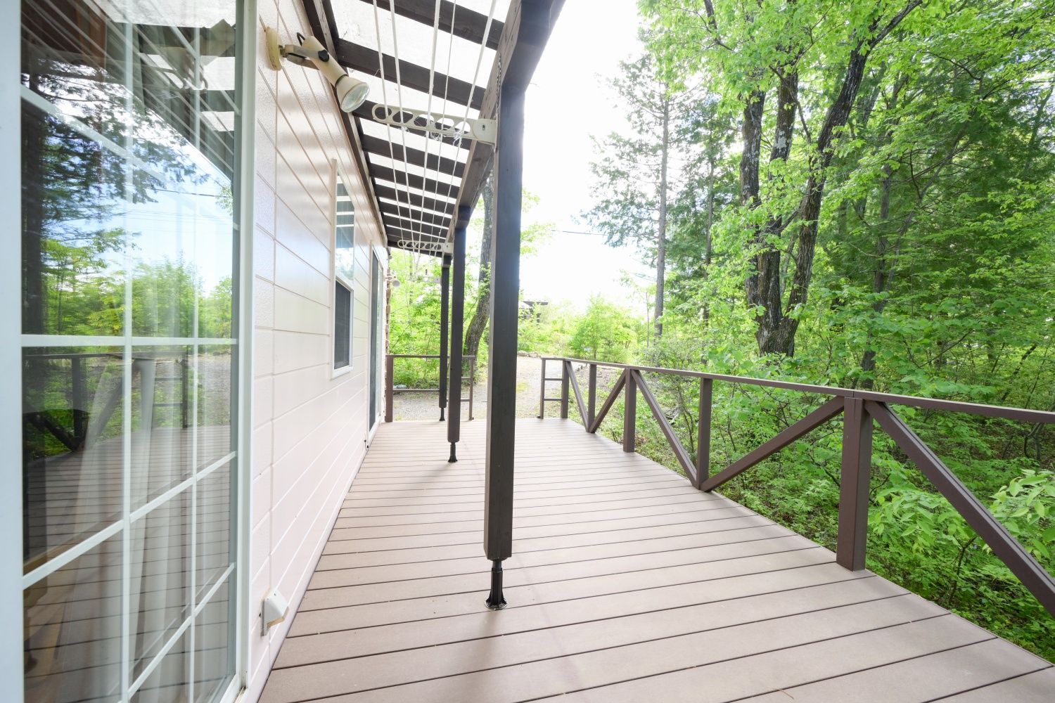Une terrasse en bois avec une rambarde en métal, donnant sur une zone boisée.