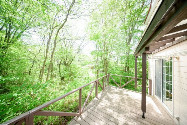 A wooden deck with a railing overlooking a forested area.