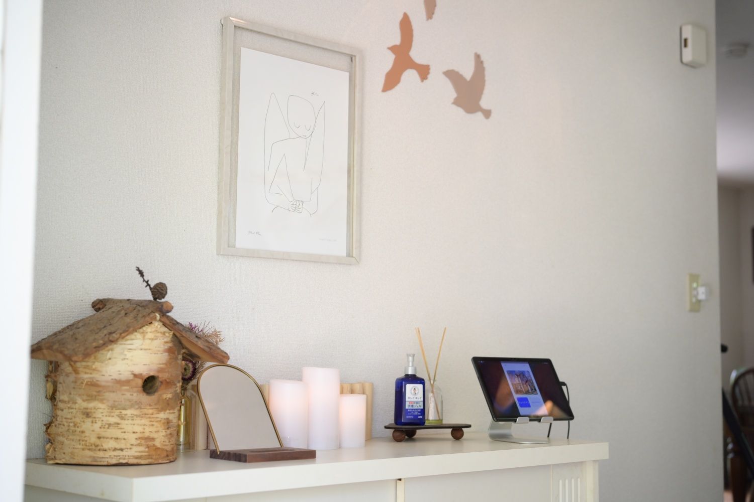 A reception desk with a framed sketch, candles, a birdhouse, and a tablet.