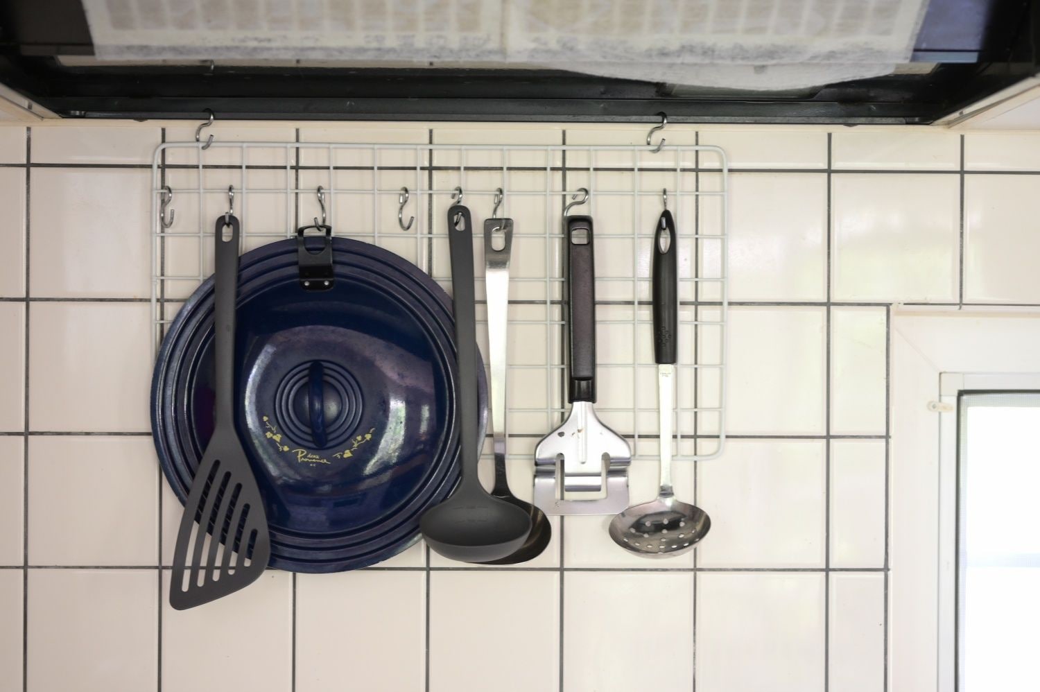 A kitchen with a hanging rack holding various utensils.