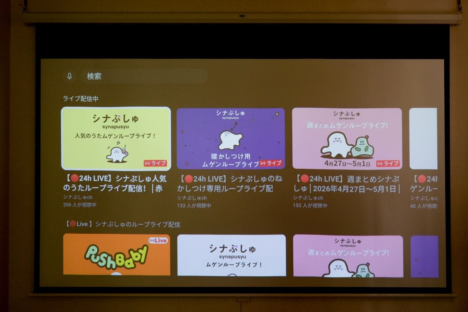 Une projection représentant une pièce dans laquelle un écran affiche différents blocs colorés, chacun étant accompagné d’un texte en japonais et de certains symboles.