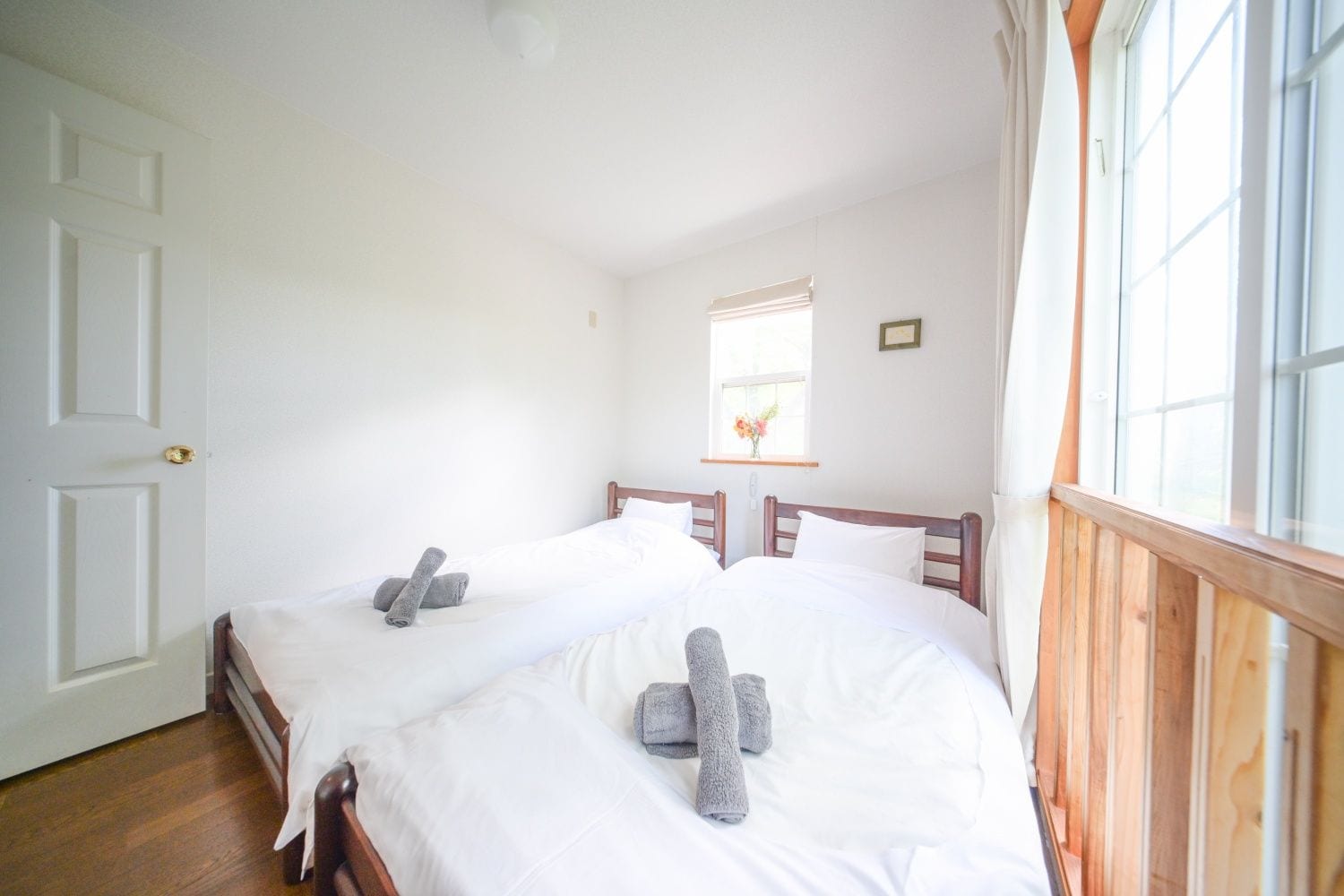 A room with two beds, a window with a view, and a door.