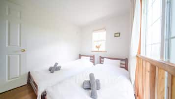 A room with two beds, a window with a view, and a door.
